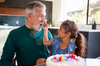 Granddaughter Celebrates Birthday With Grandfather By Putting Cake Cream On His Nose And Laughing