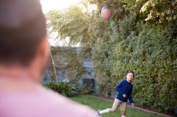 Father And Son Throwing And Catching Ball In Back Yard