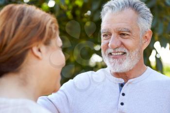 Smiling Senior Hispanic Couple Talking And Laughing In Garden At Home