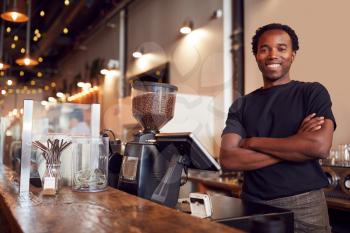 Portrait Of Male Coffee Shop Owner Standing At Sales Desk
