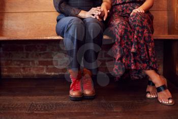 Close Up On Feet Of Same Sex Female Couple Holding Hands Sitting On Bench Together