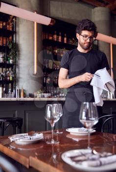 Male Waiter Polishing Glasses Before Service In Bar Restaurant