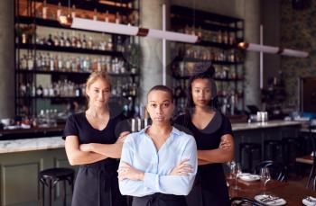 Portrait Of Female Owner Of Restaurant Bar With Team Of Waiting Staff Standing By Counter