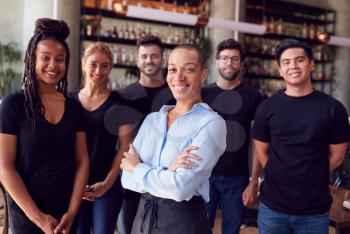 Portrait Of Female Owner Of Restaurant Bar With Team Of Waiting Staff Standing By Counter