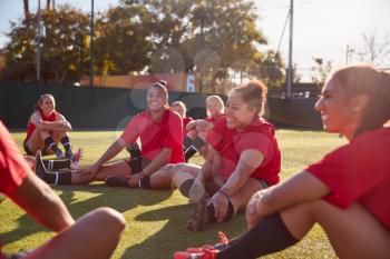 Womens Football Team Stretching Whilst Training For Soccer Match On Outdoor Astro Turf Pitch