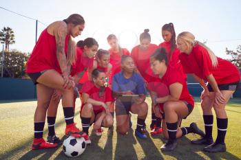Coach With Digital Tablet Discussing Tactics With Womens Football Team Training For Soccer Match