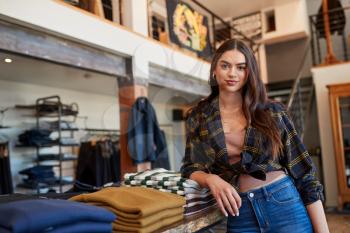 Portrait Of Smiling Female Owner Of Fashion Store Standing In Front Of Clothing Display