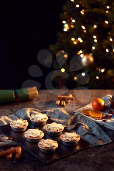 Freshly Baked Mince Pies On Table Set For Christmas With Tree Lights In Background