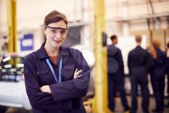 Portrait Of Female Student With Safety Glasses Studying For Auto Mechanic Apprenticeship At College