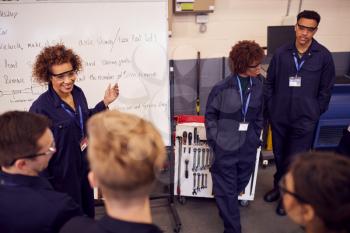 Female Tutor By Whiteboard With Students Teaching Auto Mechanic Apprenticeship At College
