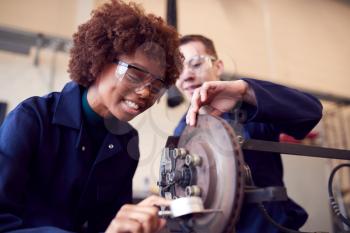 Male And Female Students Working On Car Brakes On Auto Mechanic Apprenticeship Course At College
