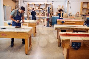 Wide Angle View Of Carpentry Workshop With Students Studying For Apprenticeship At College
