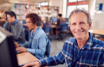 Portrait Of Male Mature Adult Student In Class Working At Computers In College Library