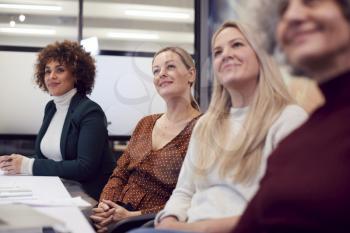 Line Of Businesswomen In Modern Office Listening To Presentation By Colleague