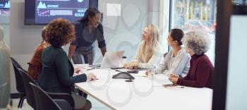 Young Businesswoman Leading Creative Meeting Of Women Collaborating Around Table In Modern Office