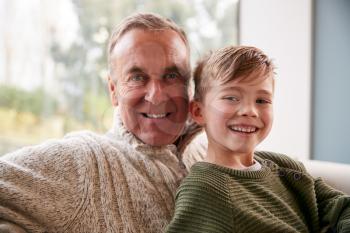 Portrait Of Grandson Sitting On Sofa At Home With Grandfather