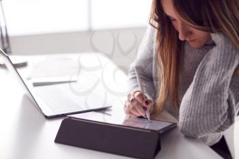 Businesswoman Working From Home Drawing On Digital Tablet Using Stylus Pen