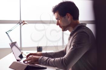 Businessman Working On Laptop At Desk In Modern Office