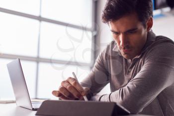 Businessman Working From Home Drawing On Digital Tablet Using Stylus Pen