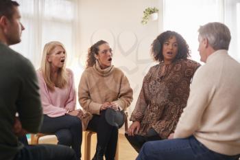 Shocked Group Consoling Man Speaking At Support Group Meeting For Mental Health Or Dependency Issues