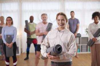 Portrait Of People In Exercise Clothing Meeting For Fitness Or Yoga Class In Community Center