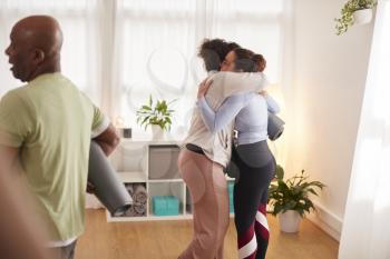 Two Women In Exercise Clothing Meeting And Hugging Before Fitness Or Yoga Class In Community Center