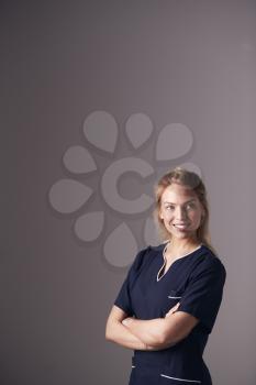 Studio Portrait Of Female Nurse Wearing Uniform Standing Against Grey Background