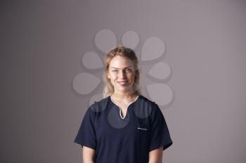 Studio Portrait Of Female Nurse Wearing Uniform Standing Against Grey Background