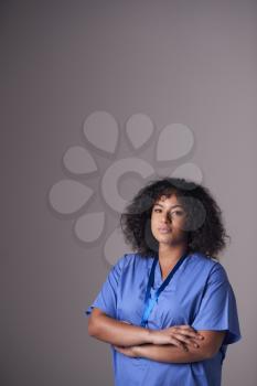 Studio Portrait Of Female Nurse Wearing Scrubs Standing Against Grey Background