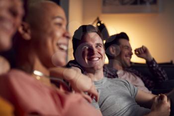 Group Of Gay Friends Sitting On Sofa At Home Watching Evening TV And Relaxing Together