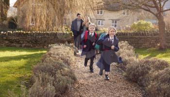Parents Returning Home From School With Children Wearing School Uniform Running Down Path
