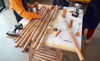 Close Up Of Team In Workshop Assembling Hand Built Sustainable Bamboo Bicycle Frame