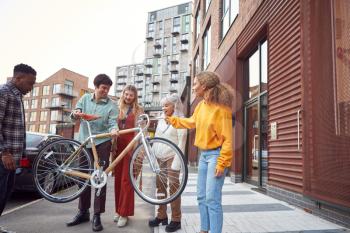 Group Of Multi-Cultural Friends On City Street Lifting Sustainable Bamboo Bicycle