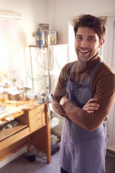 Portrait Of Smiling Male Jeweller At Bench Working In Studio