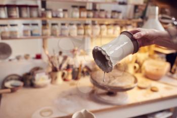 Close Up Of Potter Applying Glaze To Clay Vase In Ceramics Studio