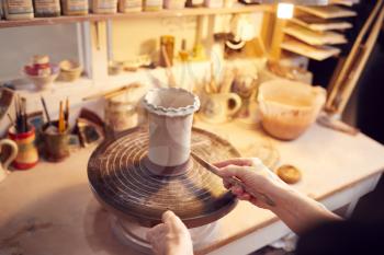 Close Up Of Potter Applying Glaze To Clay Vase In Ceramics Studio
