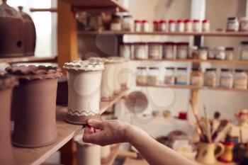 Close Up Of Potter Putting Glazed Clay Vase On Shelf In Ceramics Studio