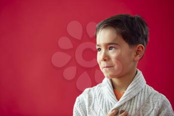 Profile Of Smiling Young Boy Against Red Studio Background