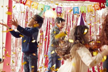 Group Of Children In Party Hats Celebrating At Birthday Party With Streamers And Gold Confetti