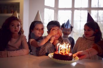 Boy Celebrating Birthday With Group Of Friends At Home Being Given Cake Decorated With Sparkler