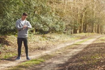Man Running In Countryside Exercising Checking Smart Watch Fitness Activity App