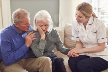 Female Doctor Giving Bad News To Senior Couple During Home Health Visit