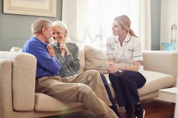 Female Doctor Giving Good News To Senior Couple During Home Health Visit