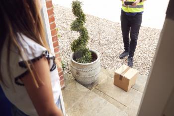 Close Up Of Delivery Driver Putting Package On Doorstep Outside House