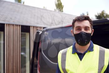 Portrait Of Delivery Driver Wearing Mask Next To Van Outside House