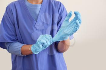 Close Up Of Female Nurse Wearing Scrubs Putting On Sterile PPE Gloves