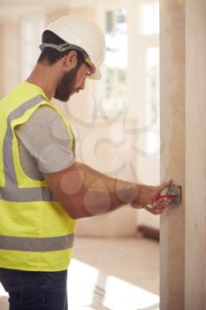 Electrician Wearing Hard Hat Fitting Light Switch At New Build Property