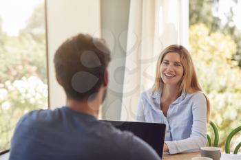 Couple With Laptop Sitting At Table Working From Home Together