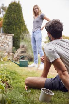 Couple Working Outdoors In Garden At Home Digging And Planting