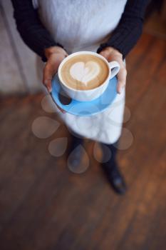 Close Up Of Waitress In Coffee Shop Holding Cup With Heart Design Poured Into Milk